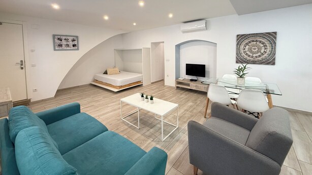 Een moderne woonkamer met een bank, een salontafel, een televisie en een eethoek met stoelen.