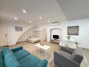 A modern living room with a sofa, a coffee table, a TV, and a dining area with chairs. - Agi Cosconilles 170 Apartamento for rent in Roses Girona. (Roses)