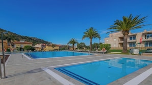 A swimming pool with clear blue water, surrounded by lounge chairs and palm trees. - Agi Rescator 321 Apartamento for rent in Roses Girona. (Rosas / Roses)