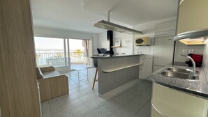 A modern kitchen with a built-in microwave, a sink, and a dining area with a bench. - Agi Pi Sunyer 4 1A Apartamento for rent in Roses Girona. (Roses)