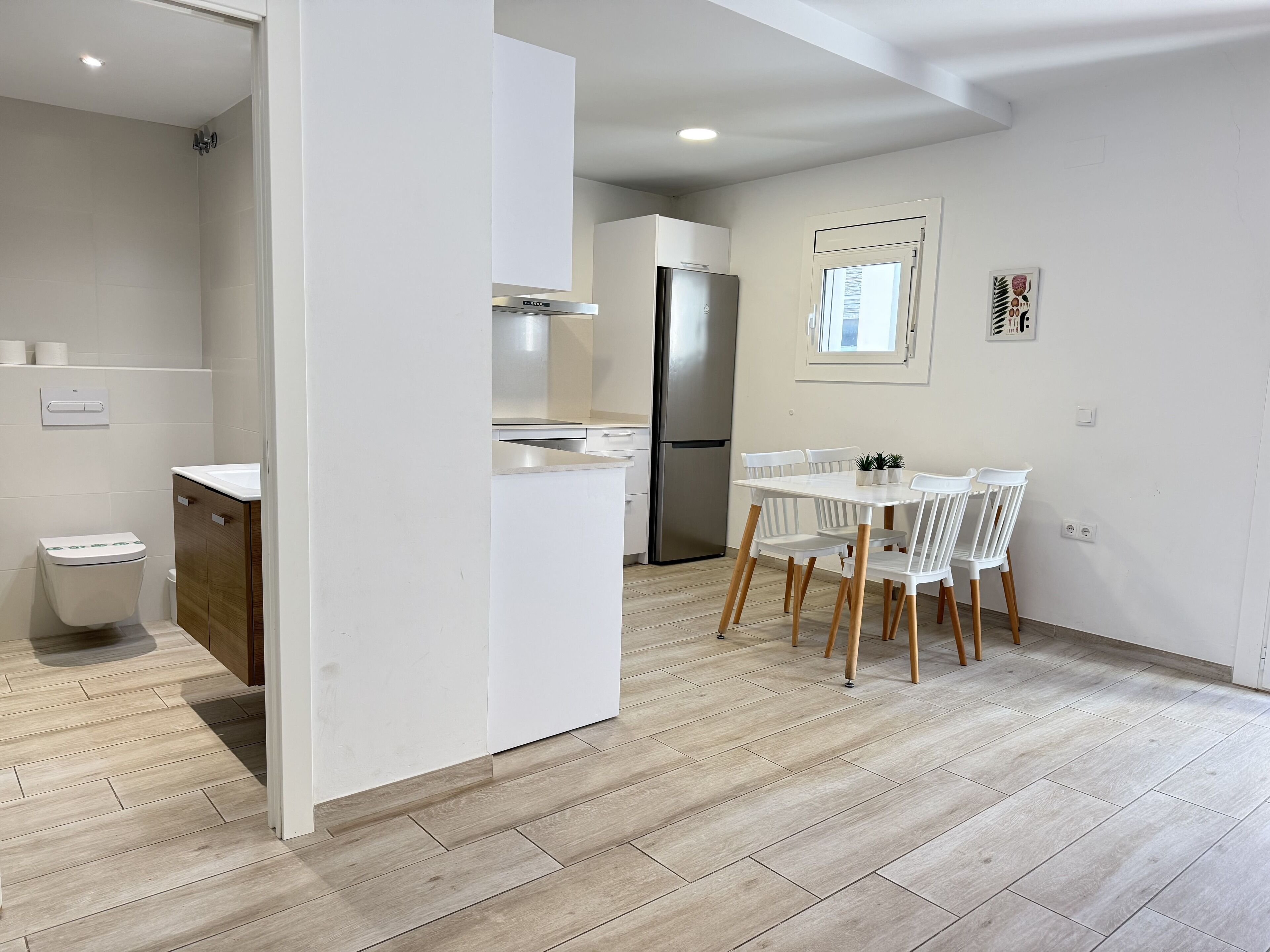 Une cuisine moderne avec des meubles blancs, un four encastré et un réfrigérateur en acier inoxydable.