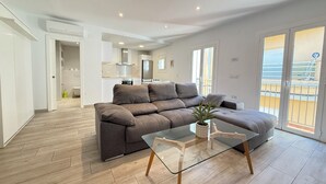 En moderne stue med en modulsofa, et sofabord i glas og udsigt til balkonen.