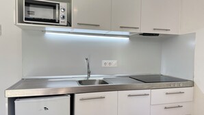 A compact kitchen with a built-in microwave, a sink, and a stove. - Agi Rescator 117 Apartamento for rent in Roses Girona. (Rosas / Roses)