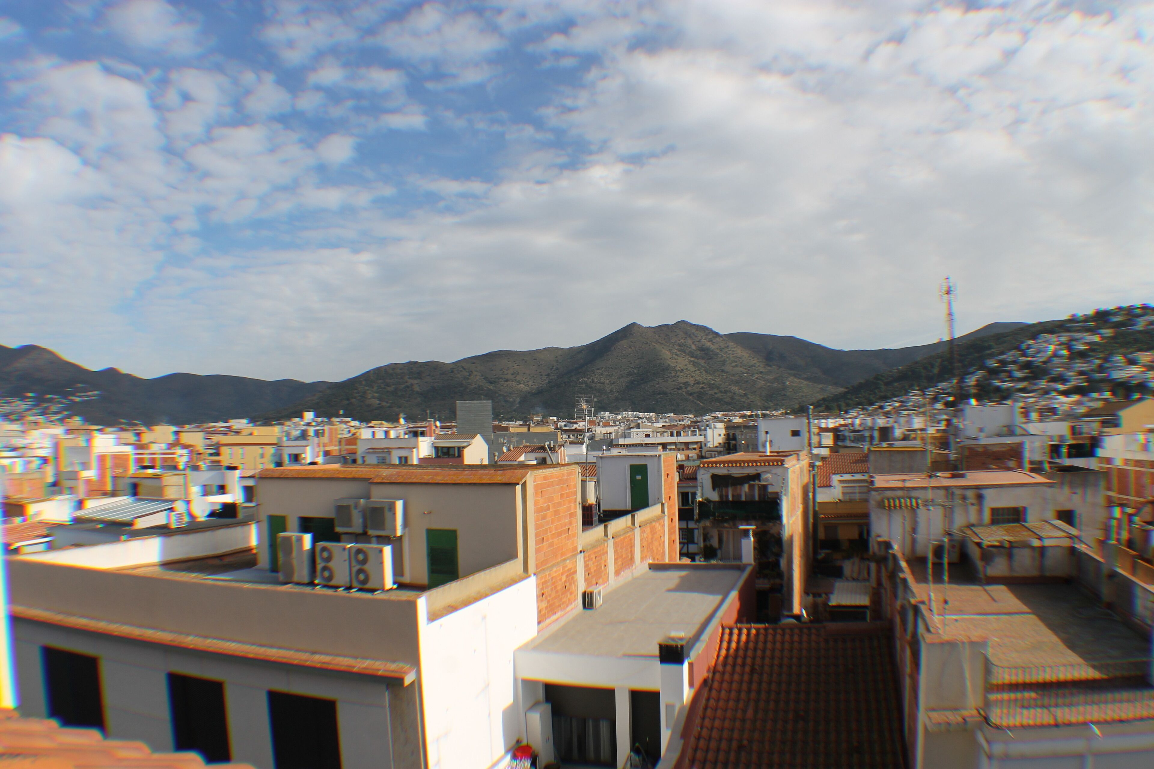 Un paisaje urbano con edificios y una montaña al fondo.