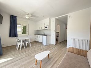 A modern kitchen with white cabinets, a microwave, and a dining area with a white table and chairs.
