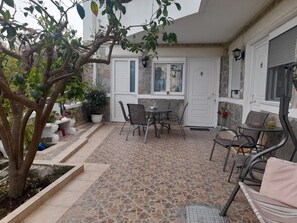 Relax in the serene patio area with a table and chairs, surrounded by lush greenery and a stone wall.