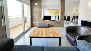 Un salon moderne avec une table basse en bois, des canapés gris et un téléviseur.
