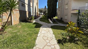 Un patio con un sendero de piedra, un árbol alto y edificios con balcones.