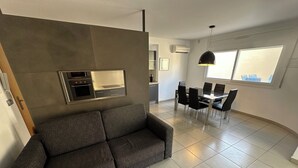 Un salon moderne avec un canapé gris, une table basse en bois et un coin repas comprenant une table et des chaises.