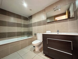 A modern bathroom with a glass-enclosed shower, a toilet, and a vanity with a mirror. - Agi Drugstore AE Apartamento for rent in Roses Girona. (Roses)