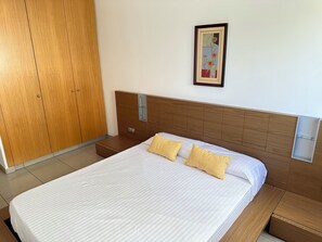 A hotel room with a large bed, wooden wardrobe, and a framed picture on the wall. - Agi Drugstore AE Apartamento for rent in Roses Girona. (Roses)