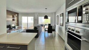 A modern kitchen with a large island, stainless steel appliances, and a dining area with a table and chairs.