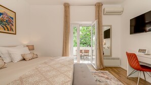 A bedroom with a bed, a desk, a chair, a TV, and a balcony. - Luxury apartment positioned in a green oasis in the middle of the city (Split)