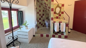 A bathroom with a checkered floor, a shower, a sink with a mirror, and a window with a view of greenery. - Agi Torre Quimeta Torre Apartamento for rent in Roses Girona. (Rosas / Roses)
