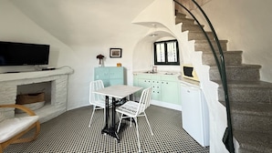 A compact living space with a television, a dining table, chairs, a kitchen area, and a staircase. - Agi Torre Quimeta Torre Apartamento for rent in Roses Girona. (Rosas / Roses)