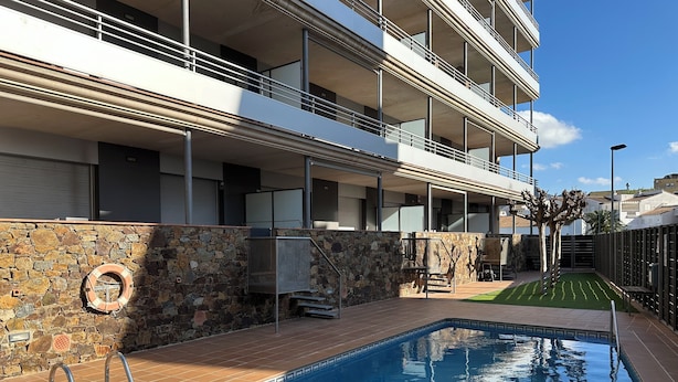 A modern hotel with a swimming pool, stone wall, and balconies. - Agi Torre Quimeta Torre Apartamento for rent in Roses Girona. (Rosas / Roses)