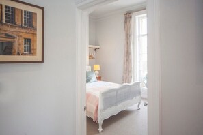 A bedroom with a bed, a lamp, a window with curtains, and a framed picture on the wall. - Beautiful City Centre Apartment (MSA) (Bath)