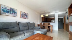 Un salon avec un canapé gris, une table basse en bois et deux tableaux accrochés au mur.