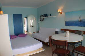 Una habitación con una cama, una mesita y una silla. Hay un reloj en la pared y un cuadro de un velero.