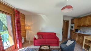 Ein gemütliches Wohnzimmer mit einem roten Sofa, einem blauen Sessel und einem gemusterten Teppich.