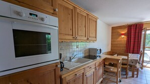 Eine Küche mit Holzschränken, einem eingebauten Backofen, einer Mikrowelle und einem Spülbecken.