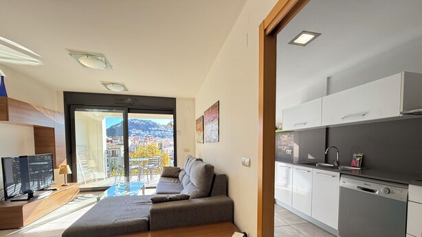 A modern apartment with a sofa, a TV, a kitchen, and a balcony with a city view. - Agi Riera Ginjolers 3B Apartamento for rent in Roses Girona. (Roses)