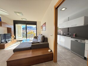 A modern apartment with a sofa, a TV, a kitchen, and a balcony with a city view. - Agi Riera Ginjolers 3B Apartamento for rent in Roses Girona. (Roses)