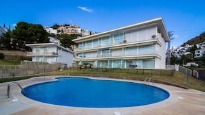 A modern two-story building with a swimming pool in front.