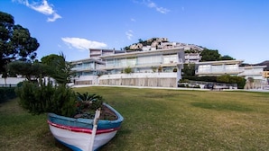 A modern building with a flat roof and large windows, situated on a grassy area with a boat in the foreground.