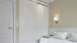 Una camera d'albergo con un letto, un armadio, un comodino e una lampada a parete.
