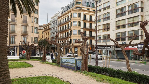 Una vista di una strada con edifici, un marciapiede e alberi.