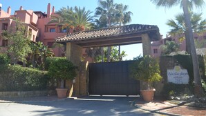 A gated entrance to a building with a tiled roof and a sign reading "Alicate playa". - URBANIZATION ALICATE PLAYA. (Marbella)