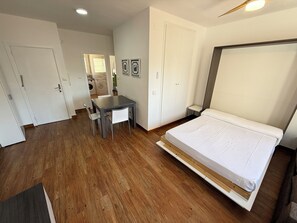 A bedroom with a bed, a dining table with chairs, a washing machine, and a small kitchen area. - Agi Josep Sabate 41 Apartamento for rent in Roses Girona. (Rosas / Roses)
