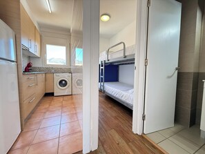 A compact kitchen with a washing machine, a sink, and a window.