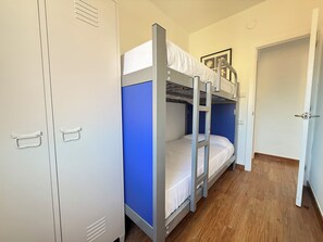 A bunk bed room with a wardrobe, a door, and a blue wall. - Agi Josep Sabate 41 Apartamento for rent in Roses Girona. (Rosas / Roses)