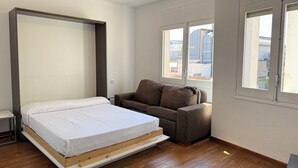 Une pièce comprenant un lit, un canapé, un ventilateur de plafond et de grandes fenêtres.