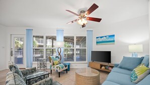 A living room with a ceiling fan, a TV, a sofa, a chair, and a coffee table.