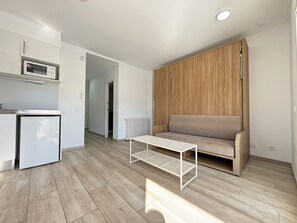 Eine moderne Wohnung mit Küchenzeile, einer Couch, einem Couchtisch und einer Wand mit Holzverkleidung.