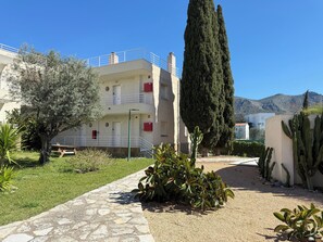 Un bâtiment avec un chemin pavé de pierres, un jardin de cactus et une montagne en arrière-plan.
