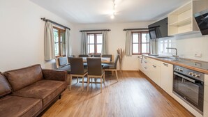 Une cuisine moderne avec des meubles en bois, un four encastré et un coin repas comprenant une table et des chaises.