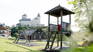 Une aire de jeux avec des balançoires et une cabane en bois.