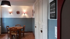 Un comedor con una mesa redonda y sillas, dos lámparas de pared y una pared con un cartel.