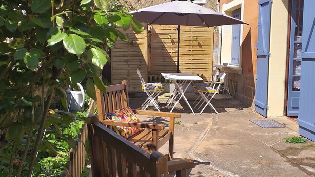 Un patio al aire libre con mobiliario de madera, una mesa y una sombrilla.
