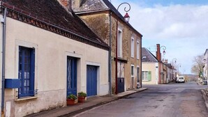 Una calle tranquila con arquitectura europea tradicional, incluyendo un edificio de techo empinado y chimenea visible.