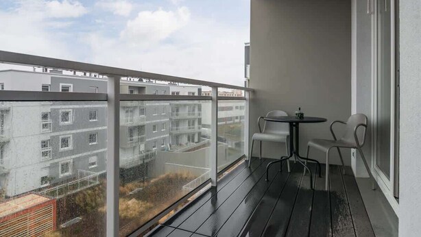 Un balcón con vistas a una zona residencial, una mesita y dos sillas.