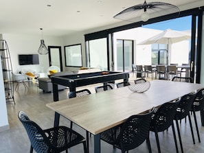 A modern dining area with a pool table, black chairs, and a large umbrella.