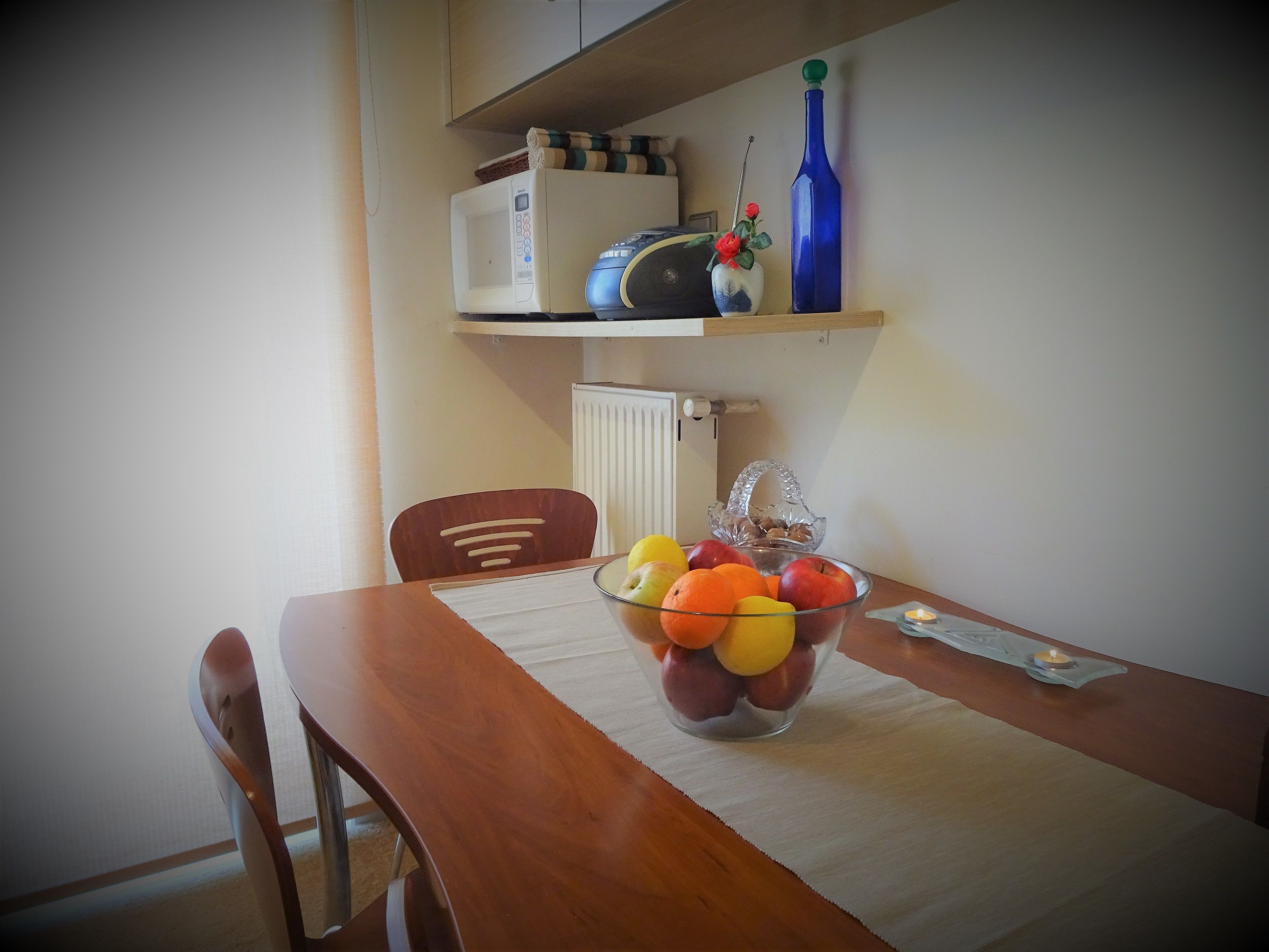 A dining table with a fruit bowl, a candle, and a small bowl of nuts.