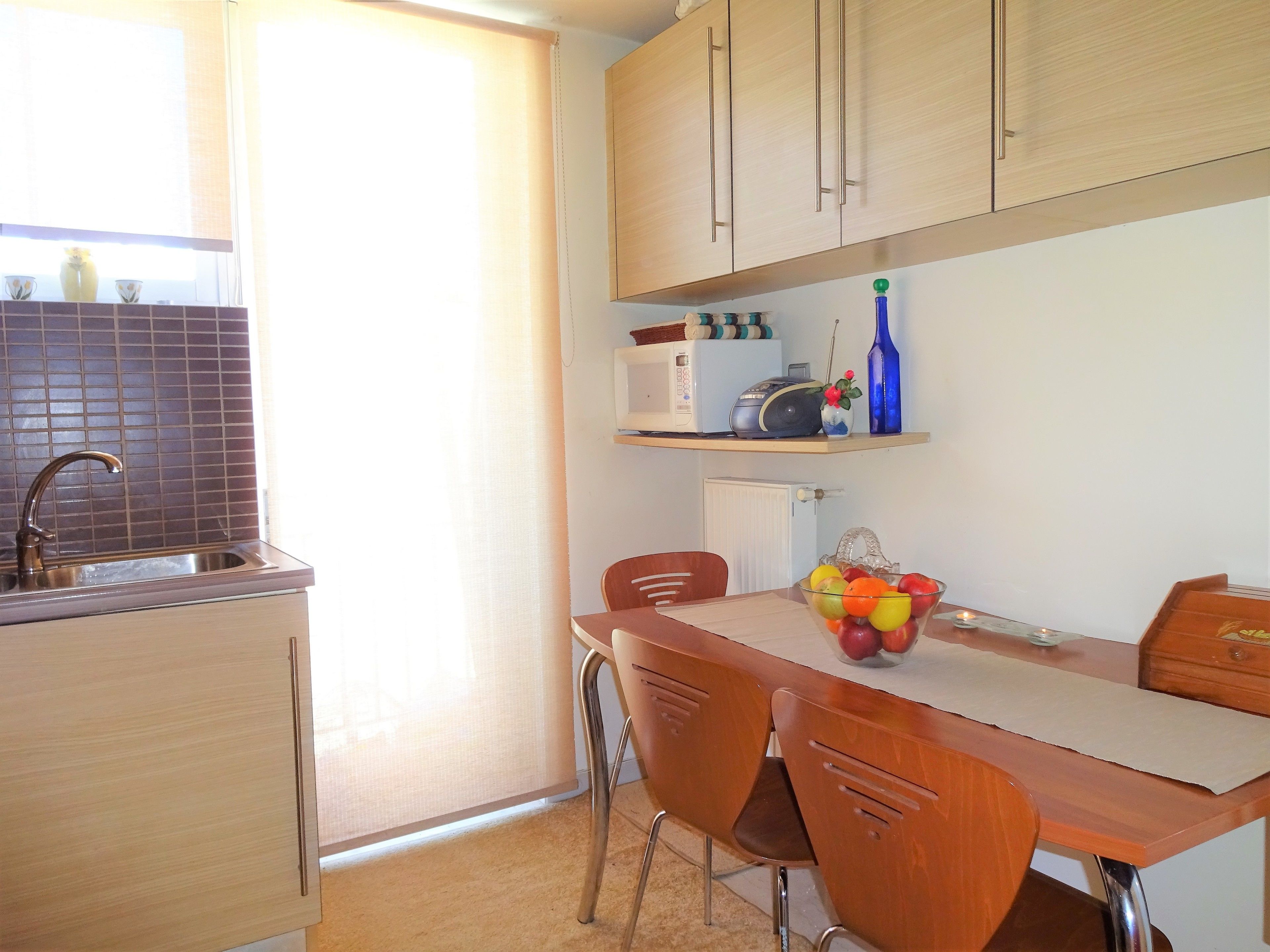 A kitchen with a sink, cabinets, a microwave, and a table with chairs.