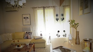 Ein gemütliches Wohnzimmer mit Sofa, Couchtisch und einem Essbereich mit Vase und Kerze.