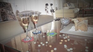 Ein Glastisch mit zwei Sektgläsern, einer Schale mit Snacks und verstreuten weißen Kugeln.
